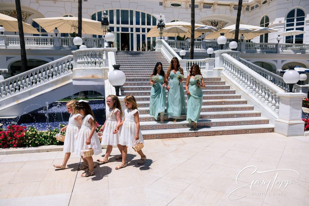 Bridesmaids and flower girls coming down the stairs at the Gran Hotel Miramar wedding venue